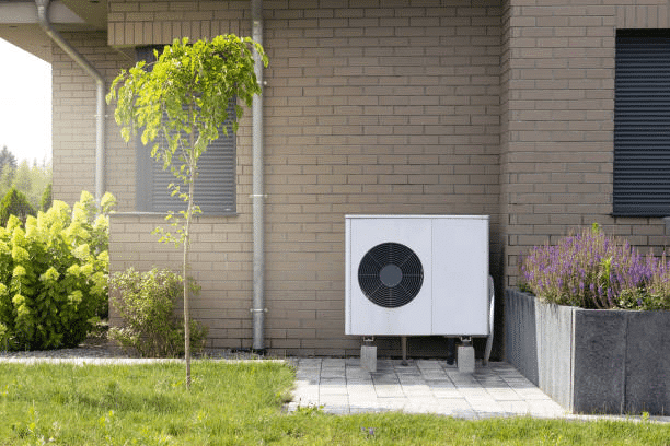 Buitenunit van een warmtepomp naast een woning