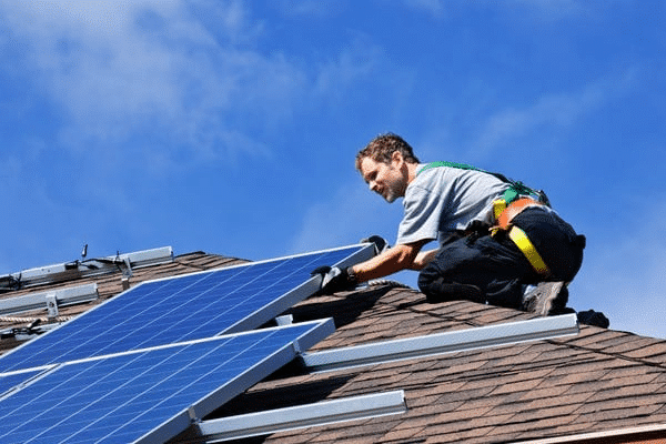 Monteur plaatst zonnepanelen op een schuin pannendak